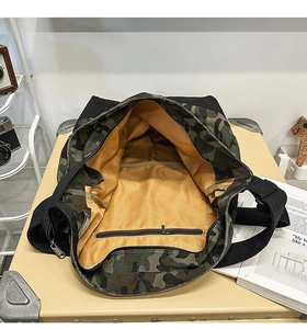 Detail view of the camouflage canvas bag showing the yellow lining and internal zipper pocket