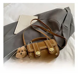 Detail einer braunen Vintage-Boston-Tasche mit Goldnieten und Bären-Anhänger