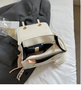 Macro view of white faux crocodile leather bag showing spacious interior and golden magnetic buckle