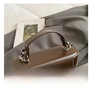 Détail de la poignée d'un sac à main vintage marron foncé avec boucles métalliques