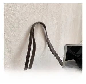 Detail of dark brown matte tote bag with white stitching and golden metal buckle