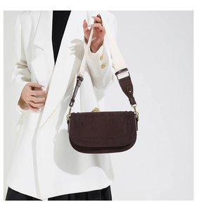 Detail of dark brown suede saddle bag with vintage gold buckle and stylish wide strap