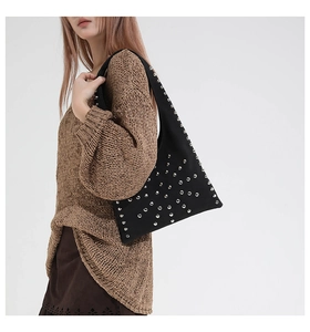 Détail d'un sac bandoulière noir orné de clous argentés avec un style punk rock sophistiqué