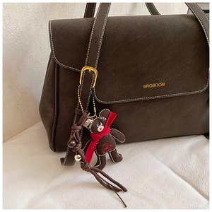 Detail of dark brown matte tote bag with gold logo and cute bear pendant charm