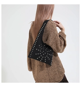 Vue détaillée d'un sac sous les bras clouté noir porté par un mannequin en pull marron