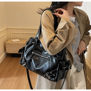 Detail of glossy black biker-style tote bag with silver zippers and buckle straps
