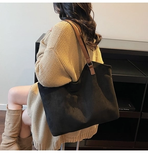 Detail of minimalist suede tote bag with brown leather straps worn with beige sweater