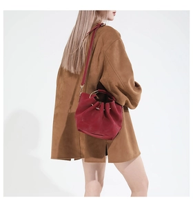 Detail of red leather bucket bag with gold metal ring handle and crossbody strap