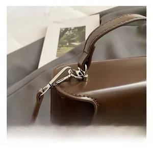 Détail du crochet rotatif argenté et du fermoir sur le sac vintage marron foncé