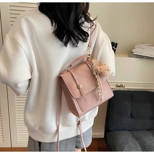 Piccola borsa quadrata rosa goffrata con foulard e orsetto indossata da modella