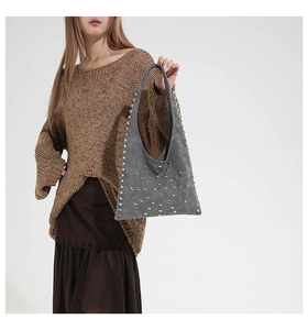 Détail du sac cabas en daim gris foncé avec clous argentés et structure triangulaire