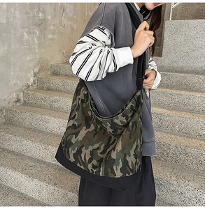 Detailed view of the large camouflage canvas tote bag worn by a model on stairs