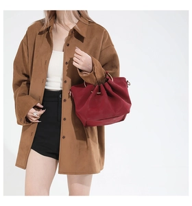 Detail of red drawstring bucket bag with gold ring handle and soft ruched leather texture