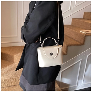 Sac boîte chic en cuir verni blanc crème brillant avec fermoir argenté porté par un mannequin