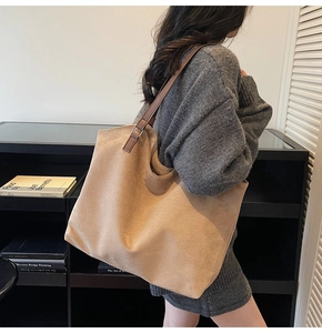 Detail of minimalist suede tote bag with brown leather straps shown on shoulder