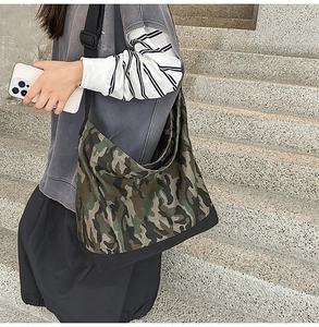 Detail of large camo canvas crossbody bag with adjustable wide strap and reinforced black base