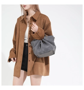 Detail of grey bucket bag with drawstring pleats paired with a brown suede shirt