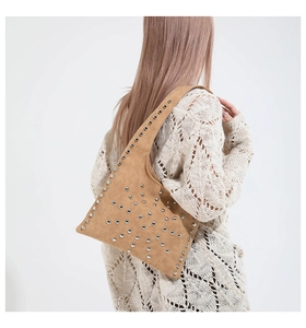 Détail d'un sac à bandoulière en daim marron avec rivets argentés et style bohème chic