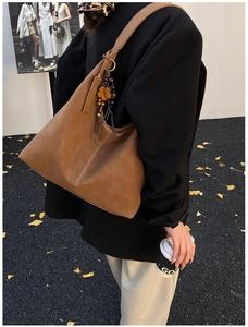 Detail of vintage matte brown tote bag with contrast stitching and clover charm