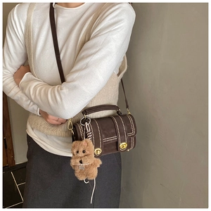 Detail einer dunkelbraunen Vintage-Handtasche mit Nieten und süßem Plüsch-Anhänger