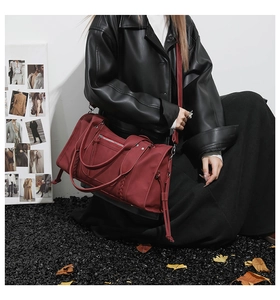 Close-up of wine red travel bag with woven handle details and stylish shoulder strap