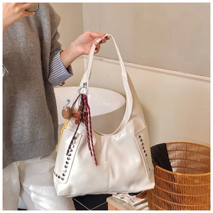 Detail view of large cream hobo tote with silver rivets and plush bear charm accessory