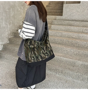 Detail view of large camo canvas crossbody bag with adjustable strap and reinforced base