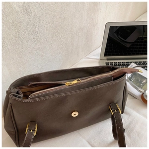 Detail of the high-quality gold metal zipper and magnetic closure on dark brown leather tote
