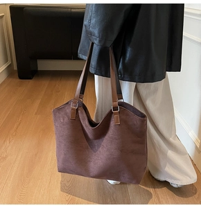 Detail of a large brown faux suede tote bag with leather straps and silver metal hardware