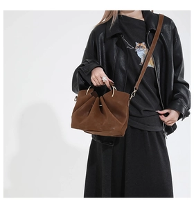 Brown suede-texture bag featuring natural pleats, gold ring handle, and shoulder strap