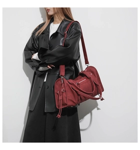 Detail of burgundy travel bag with zipper pockets and adjustable shoulder strap