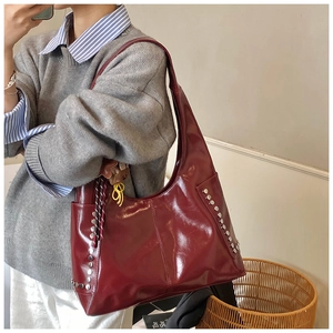 Detail of burgundy glossy leather hobo bag with vertical silver rivet studs on the side