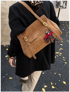 Detail view of large brown suede tote bag with metal buckles and cute bear charm