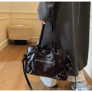 Detail of dark brown tote bag with retro oil wax leather finish and silver metal buckles