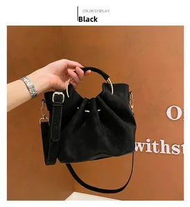 Detail of black drawstring tote bag with gold metal handle and matte leather texture