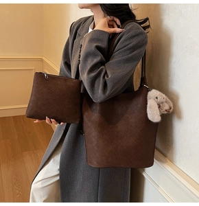 Brown woven tote and clutch set with a cute plush bunny charm on a minimalist background