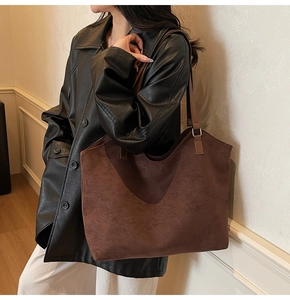 Macro detail of high-capacity dark brown suede tote bag featuring smooth matte texture
