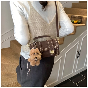 Dettaglio della borsa Boston in camoscio marrone con borchie dorate e ciondolo a cane