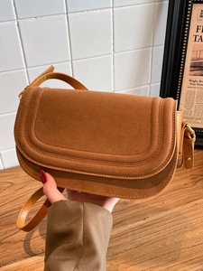 Caramel brown saddle crossbody bag with suede flap and smooth leather texture for women