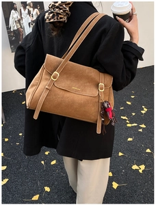 Close-up of caramel suede tote bag with golden buckle and stylish doll charm