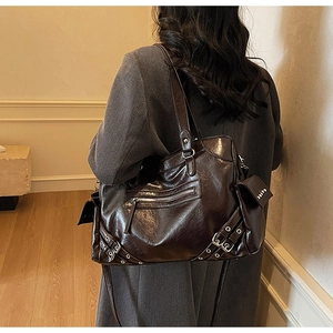 Detail of dark brown glossy leather tote featuring retro motorcycle style and metal buckles