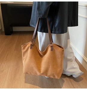 Close-up of brown suede tote bag with leather straps on model in casual chic outfit
