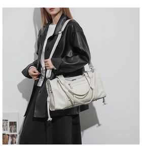 Detail of white leather travel bag featuring woven texture and adjustable shoulder strap