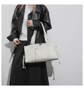 Detail of white leather shoulder bag with woven straps and front zipper pocket