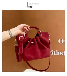 Detail of red pleated leather tote bag featuring elegant golden circular metal handles