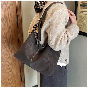 Detail of retro dark brown matte tote bag with contrast stitching and beaded tassel charm
