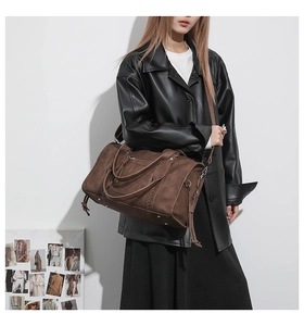 Detail of a large brown Boston travel bag with side woven texture and adjustable strap