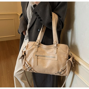 Detail view of large beige tote bag worn by model showing multi-pocket design and retro style