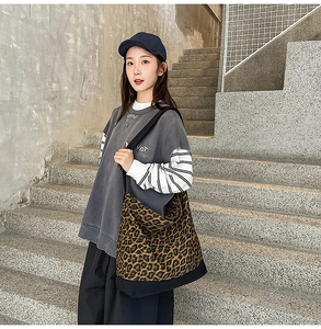 Macro shot of large leopard print canvas tote bag featuring black reinforced base and strap