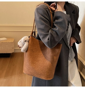 Detailed view of brown woven leather tote bag with white plush rabbit pendant
